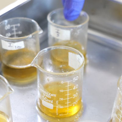 Beakers with yellow liquid on a metal surface